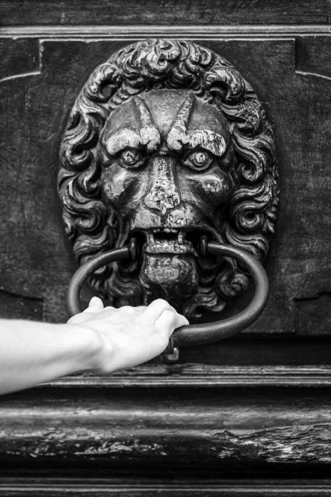 De Passage, une main saisit l'anneau de bronze d'une porte de la Vieille-Ville de Genève